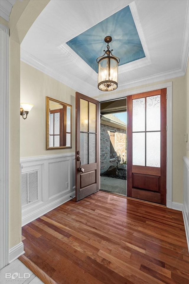 foyer entrance with a chandelier, hardwood / wood-style floors, crown molding, and french doors