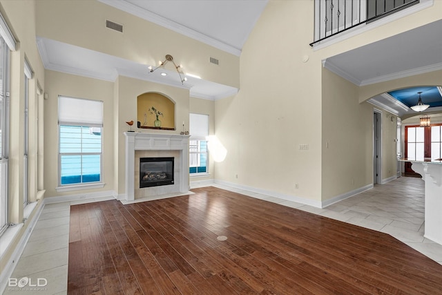 unfurnished living room featuring a fireplace, light wood-type flooring, plenty of natural light, and ornamental molding