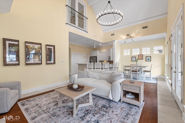 living room with french doors, a notable chandelier, a high ceiling, and light hardwood / wood-style floors