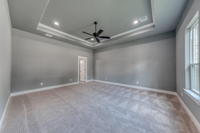 spare room with ornamental molding, a tray ceiling, ceiling fan, and light colored carpet