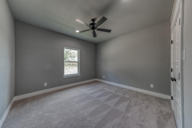 spare room with a textured ceiling, ceiling fan, and light carpet