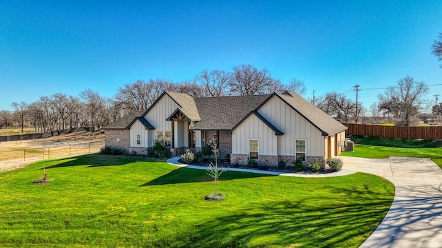 view of front of property featuring a front yard, fence, board and batten siding, and roof with shingles