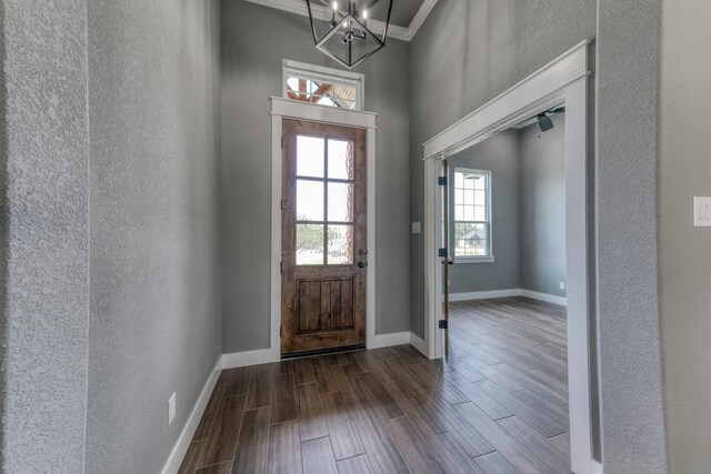 entrance foyer with wood tiled floors, a textured wall, baseboards, a high ceiling, and a chandelier