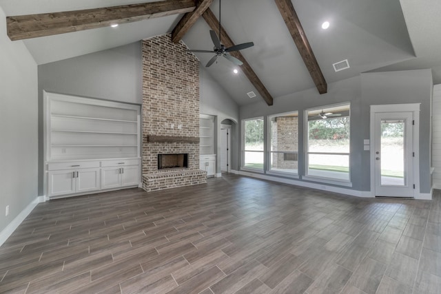 unfurnished living room featuring a brick fireplace, built in shelves, ceiling fan, beam ceiling, and high vaulted ceiling