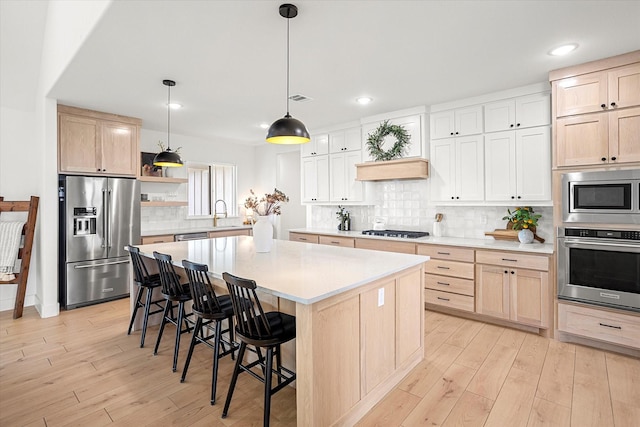 kitchen with a center island, light hardwood / wood-style floors, stainless steel appliances, and hanging light fixtures