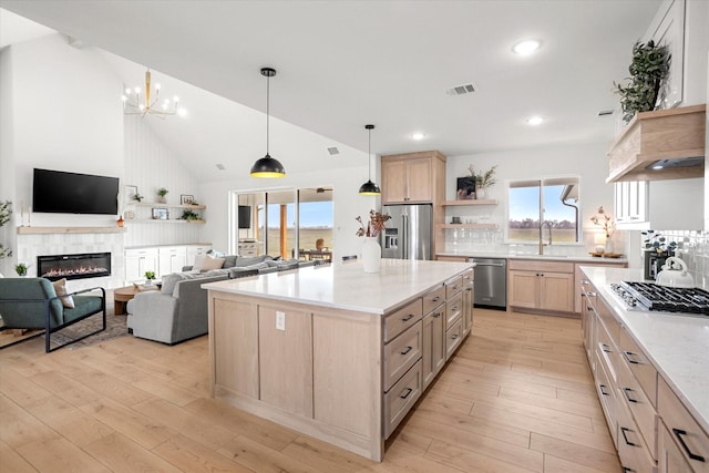 kitchen with a fireplace, light brown cabinetry, tasteful backsplash, a kitchen island, and stainless steel appliances