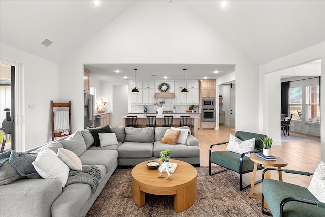 living room with light hardwood / wood-style flooring and high vaulted ceiling