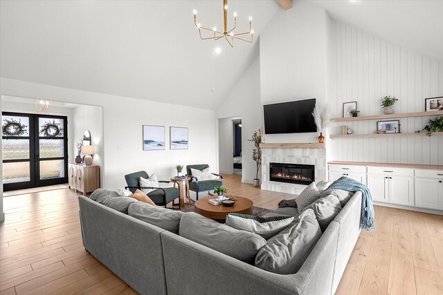 living room featuring beam ceiling, a fireplace, high vaulted ceiling, and light hardwood / wood-style flooring