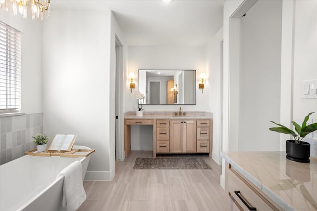 bathroom featuring a washtub, wood-type flooring, vanity, and a chandelier