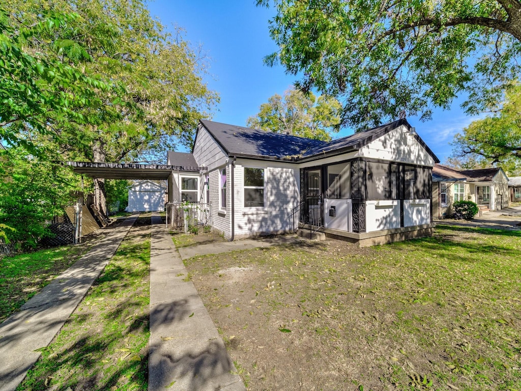 view of front of home with a carport, a sunroom, and a front yard