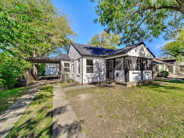 view of front of home with a carport, a sunroom, and a front yard