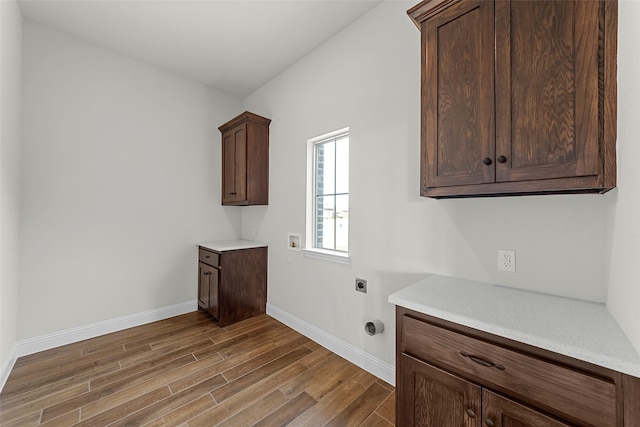 laundry area with hookup for an electric dryer, hookup for a washing machine, dark hardwood / wood-style floors, and cabinets