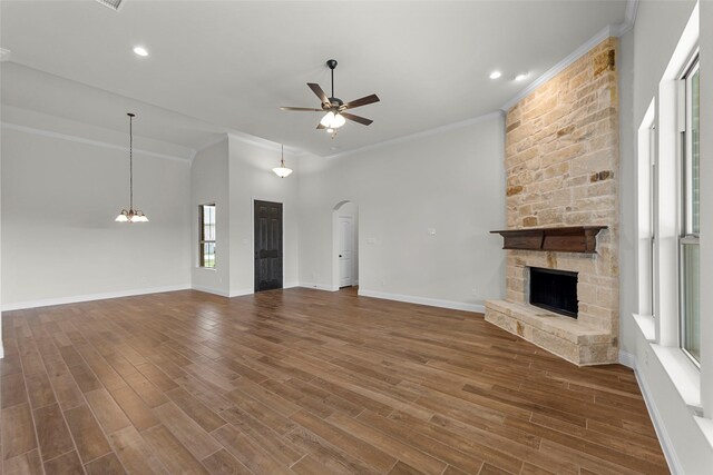 unfurnished living room with a towering ceiling, ceiling fan, crown molding, a fireplace, and dark hardwood / wood-style floors