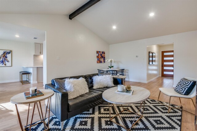 living room with vaulted ceiling with beams and light hardwood / wood-style floors