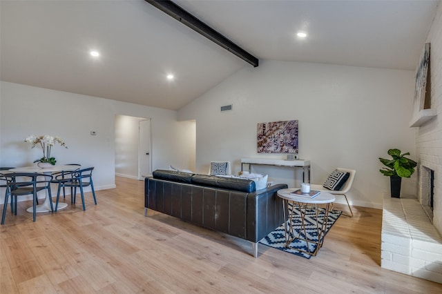 living room with a fireplace, lofted ceiling with beams, and light hardwood / wood-style flooring