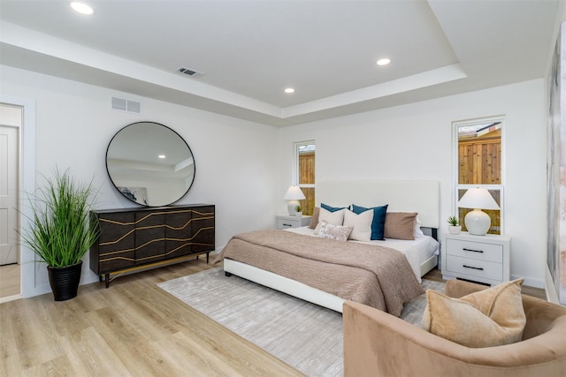 bedroom with a tray ceiling and light hardwood / wood-style flooring