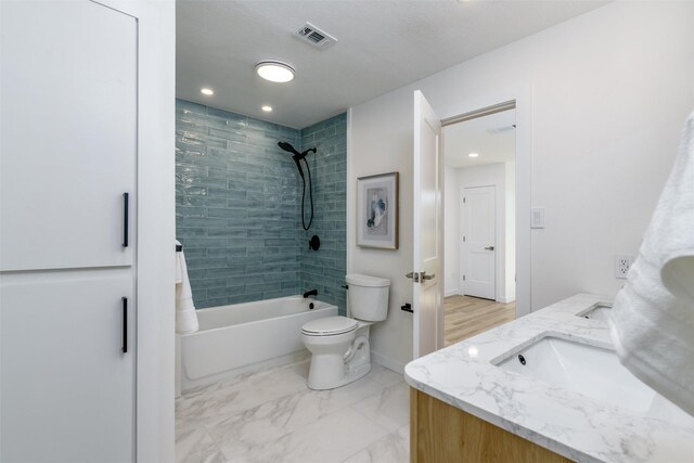 full bathroom with vanity, tiled shower / bath combo, and toilet