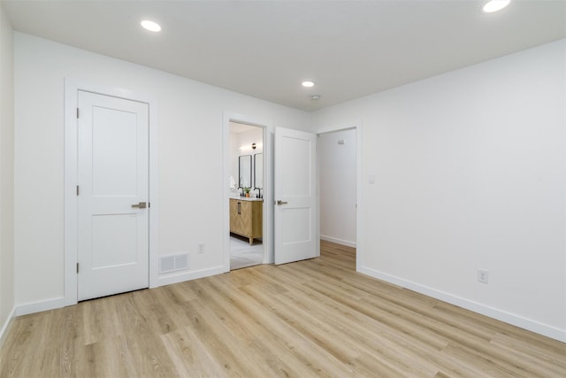 unfurnished bedroom featuring light wood-type flooring and ensuite bath