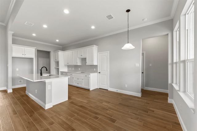 kitchen featuring an island with sink, sink, pendant lighting, and white cabinets