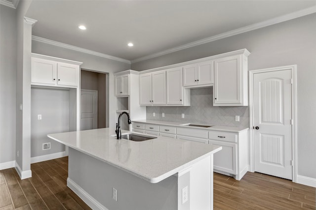 kitchen with dark hardwood / wood-style flooring, sink, an island with sink, and white cabinets