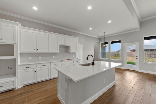 kitchen featuring white cabinetry, sink, a center island with sink, and decorative backsplash