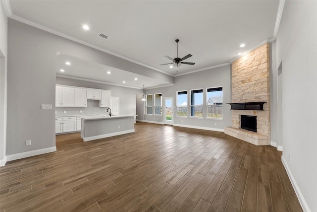 unfurnished living room with dark hardwood / wood-style flooring, ornamental molding, ceiling fan, and a fireplace