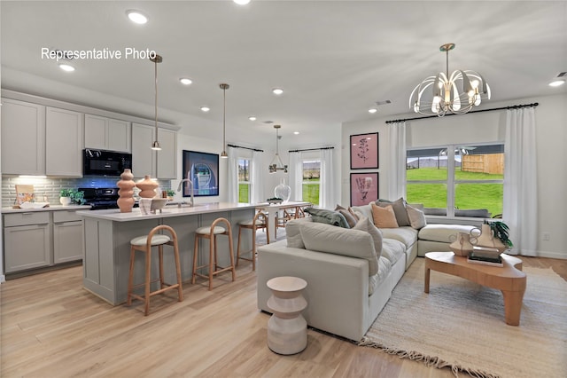 living room with a chandelier, sink, and light hardwood / wood-style flooring