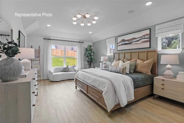 bedroom with light hardwood / wood-style floors, lofted ceiling, and an inviting chandelier