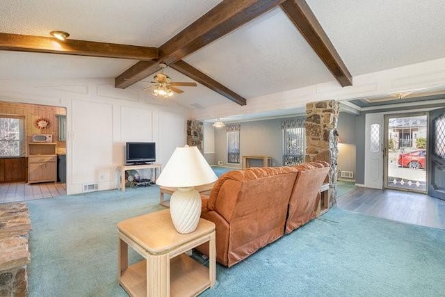 living room with ceiling fan, lofted ceiling with beams, and light carpet