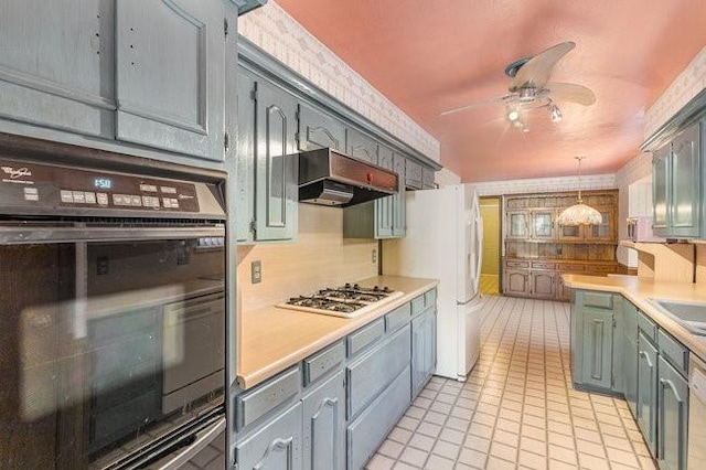 kitchen featuring pendant lighting, ceiling fan, gas stovetop, custom range hood, and oven