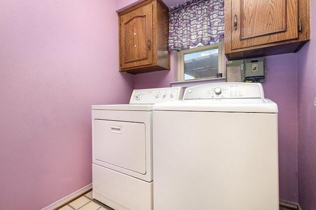 clothes washing area featuring cabinets, washing machine and dryer, and light tile patterned floors