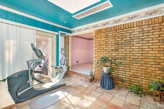 exercise area with ornamental molding and brick wall