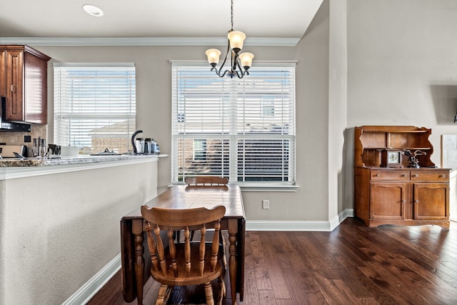 dining area with a notable chandelier, a healthy amount of sunlight, dark hardwood / wood-style flooring, and ornamental molding