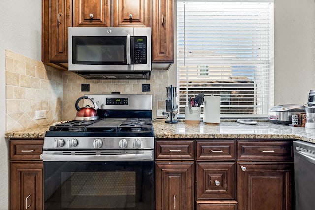 kitchen featuring backsplash, stainless steel appliances, and light stone counters