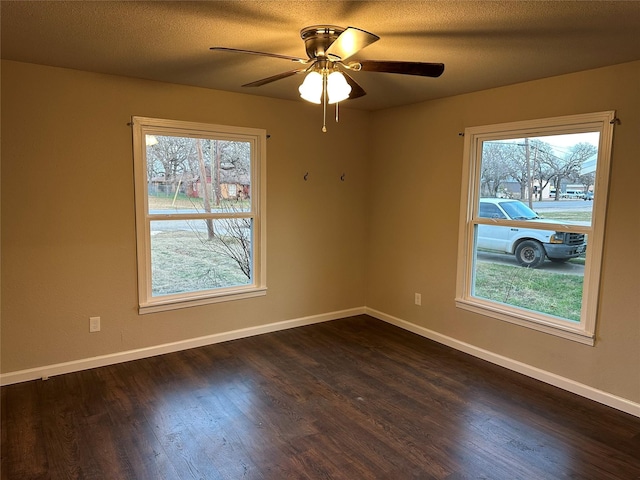 spare room featuring a wealth of natural light, dark hardwood / wood-style flooring, ceiling fan, and a textured ceiling