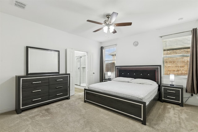 carpeted bedroom with ensuite bath and ceiling fan