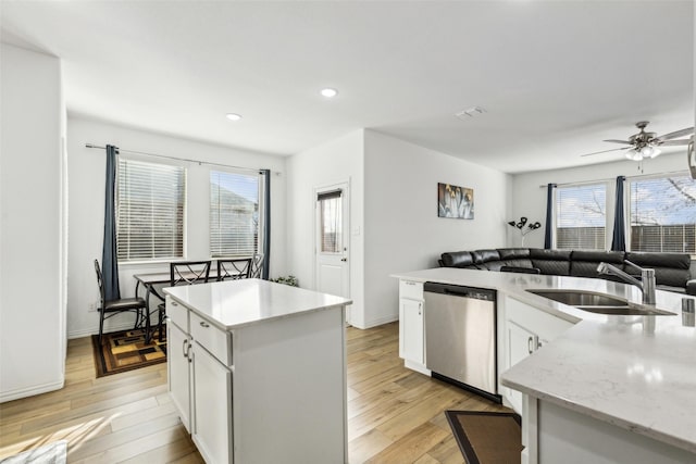 kitchen featuring dishwasher, sink, a kitchen island, light hardwood / wood-style flooring, and white cabinets