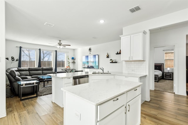 kitchen with sink, stainless steel dishwasher, tasteful backsplash, a kitchen island, and kitchen peninsula