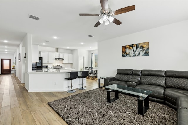 living room with ceiling fan and light hardwood / wood-style flooring