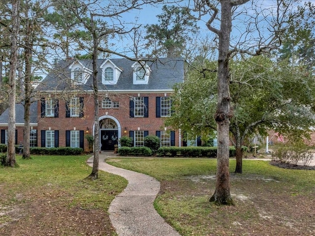 colonial-style house with brick siding and a front yard