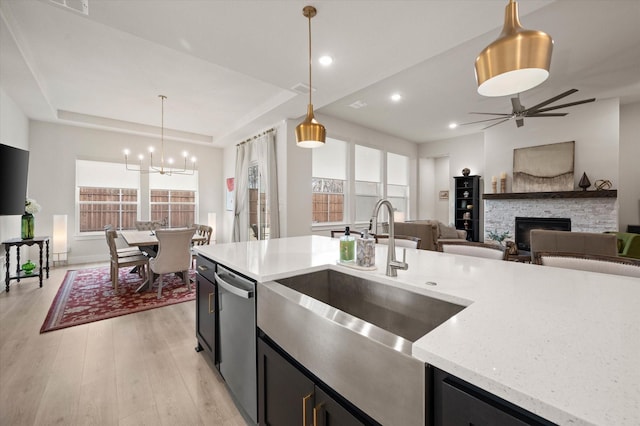 kitchen with dishwasher, pendant lighting, a stone fireplace, and a wealth of natural light