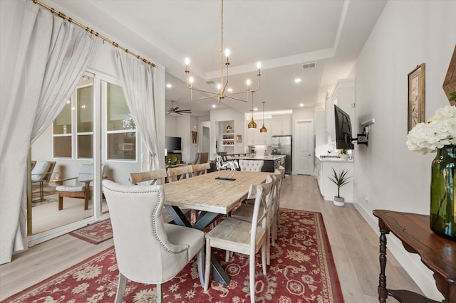 dining room featuring light wood-type flooring and ceiling fan with notable chandelier