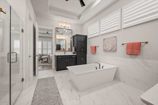 bathroom featuring vanity, a raised ceiling, tile walls, and independent shower and bath