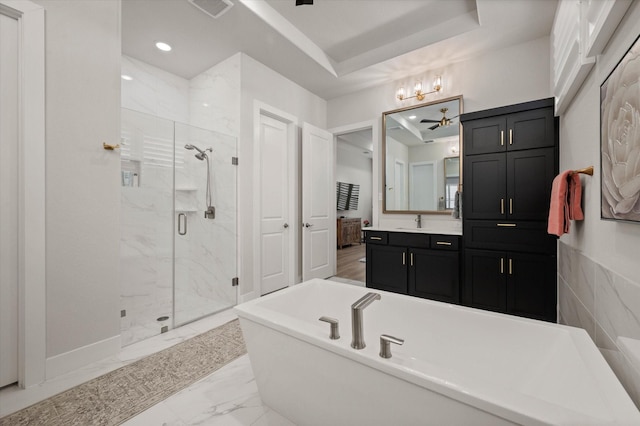 bathroom featuring plus walk in shower, vanity, a tray ceiling, and ceiling fan