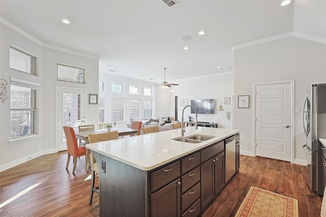 kitchen with dark brown cabinets, ceiling fan, an island with sink, and dark wood-type flooring