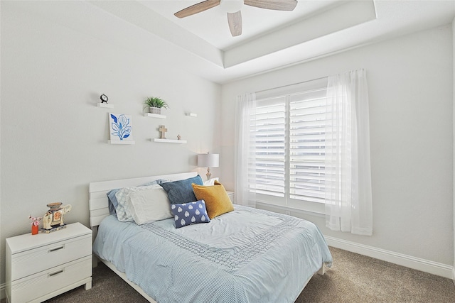 carpeted bedroom featuring a raised ceiling and ceiling fan