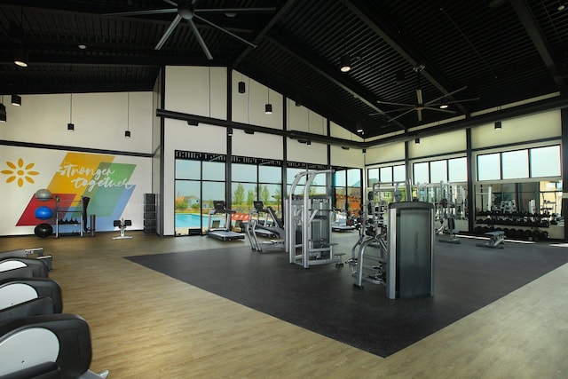 exercise room with hardwood / wood-style floors and a towering ceiling