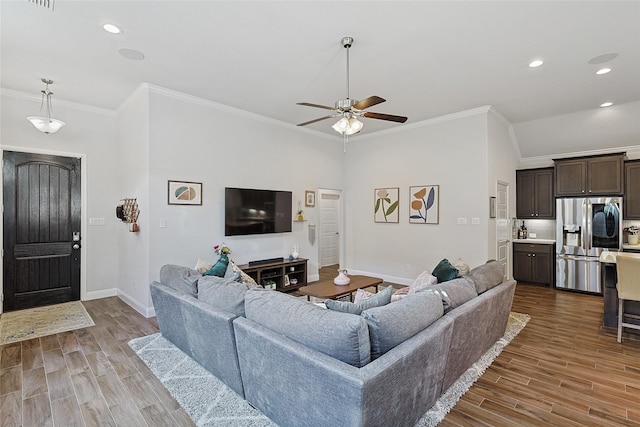 living room with hardwood / wood-style flooring, ceiling fan, and ornamental molding