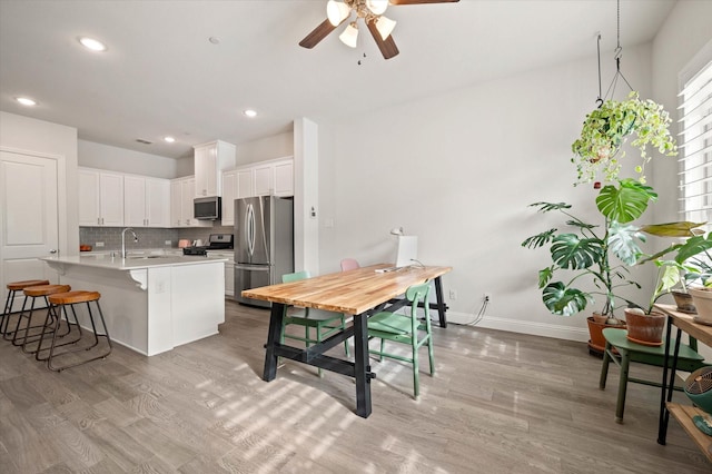 dining area featuring ceiling fan, light hardwood / wood-style floors, and sink