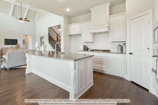 kitchen with white cabinetry, premium range hood, sink, and an island with sink